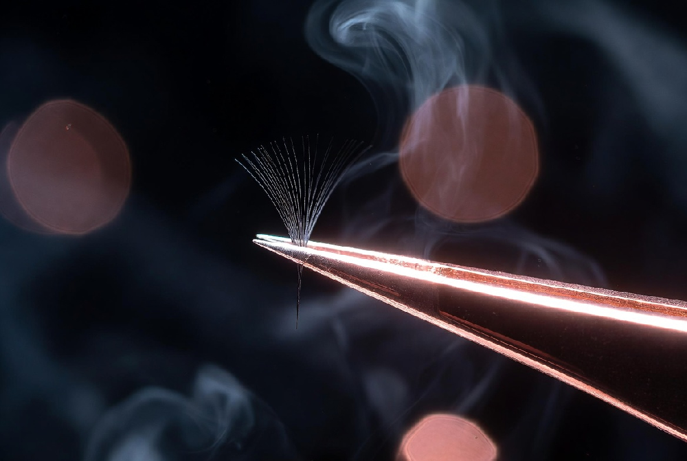 Premium straight lash tweezers picking up a single 0.15mm classic eyelash extension with perfect precision